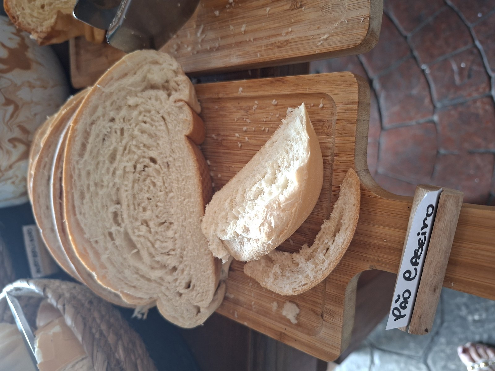 Pão caseiro fatiado em tábua de madeira, com o miolo aberto